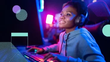 Persona jugando en computadora con auriculares, luces de colores.