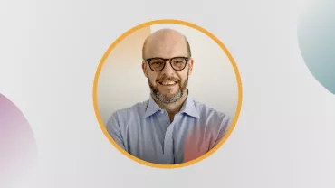 Retrato de un hombre calvo con barba, usando gafas, en un marco redondo.