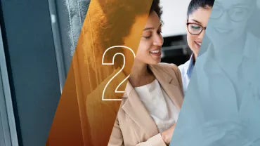 Dos personas sonríen y miran un dispositivo.