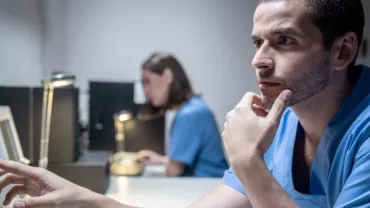 Hombre en uniforme azul observa atentamente una pantalla.