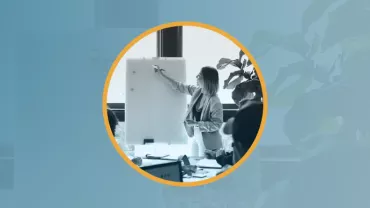 Una persona escribiendo en una pizarra durante una reunión.