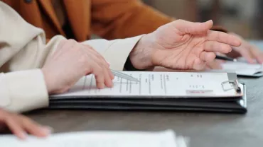 Manos sobre la mesa revisando documentos en carpetas.