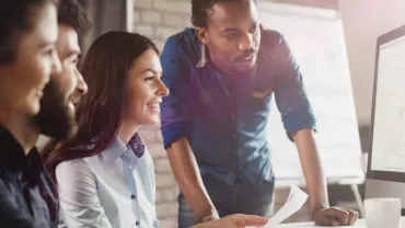 Grupo de personas trabajando frente a una computadora.
