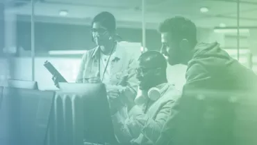 Personas colaborando en una oficina con computadores.