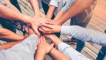 Grupo de personas uniendo sus manos en señal de trabajo en equipo.