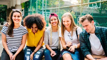 Grupo de jóvenes sentados al aire libre, sonrientes.