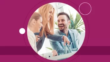 Tres personas sonríen y conversan en una oficina.