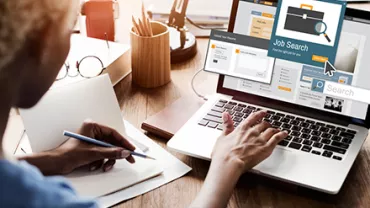 Persona usando laptop en búsqueda de empleo.