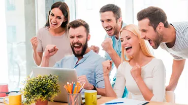 Grupo de personas celebrando frente a una computadora portátil.