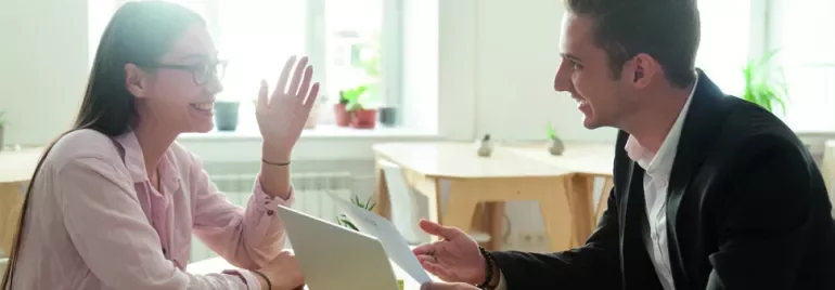 Dos personas sonríen mientras conversan en una oficina luminosa.
