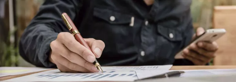 Persona revisando gráficos financieros y usando un teléfono móvil.