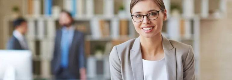 Mujer sonriente con gafas en una oficina moderna.