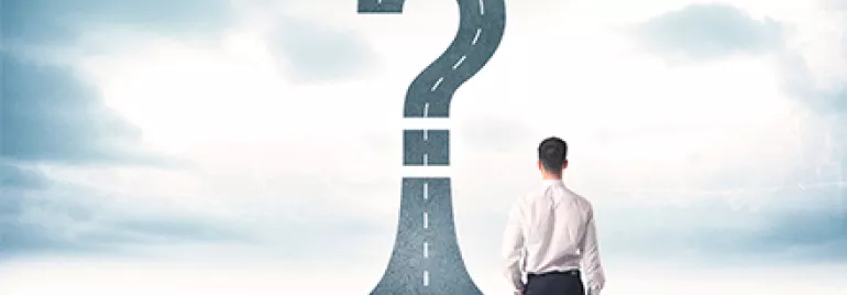 Hombre de pie frente a un camino que termina en un signo de interrogación.