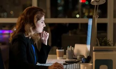 Mujer trabajando en computadora en una oficina de noche.