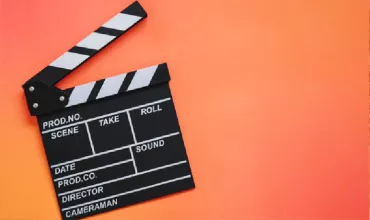 Claqueta de cine sobre fondo naranja.