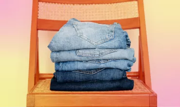 Pila de jeans vaqueros azules sobre una silla de madera.