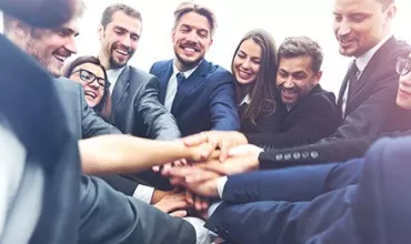 Grupo de personas en traje juntando las manos en señal de unidad.