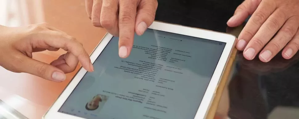 Dos personas revisan un documento digital en una tableta.