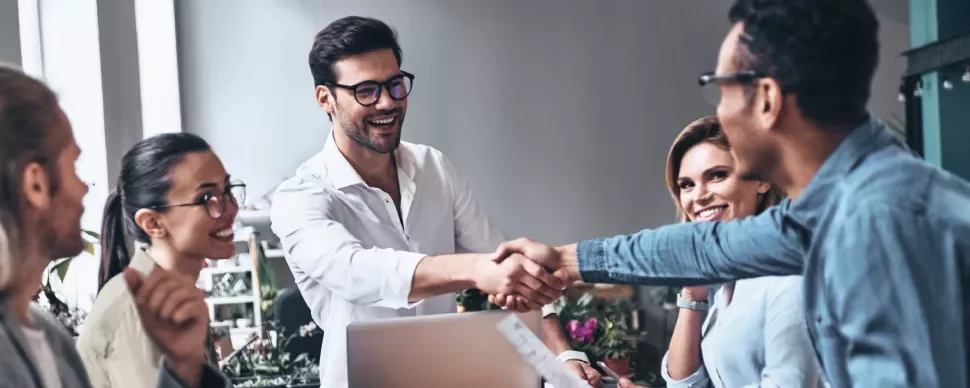 Personas en una reunión sonríen y se dan la mano.
