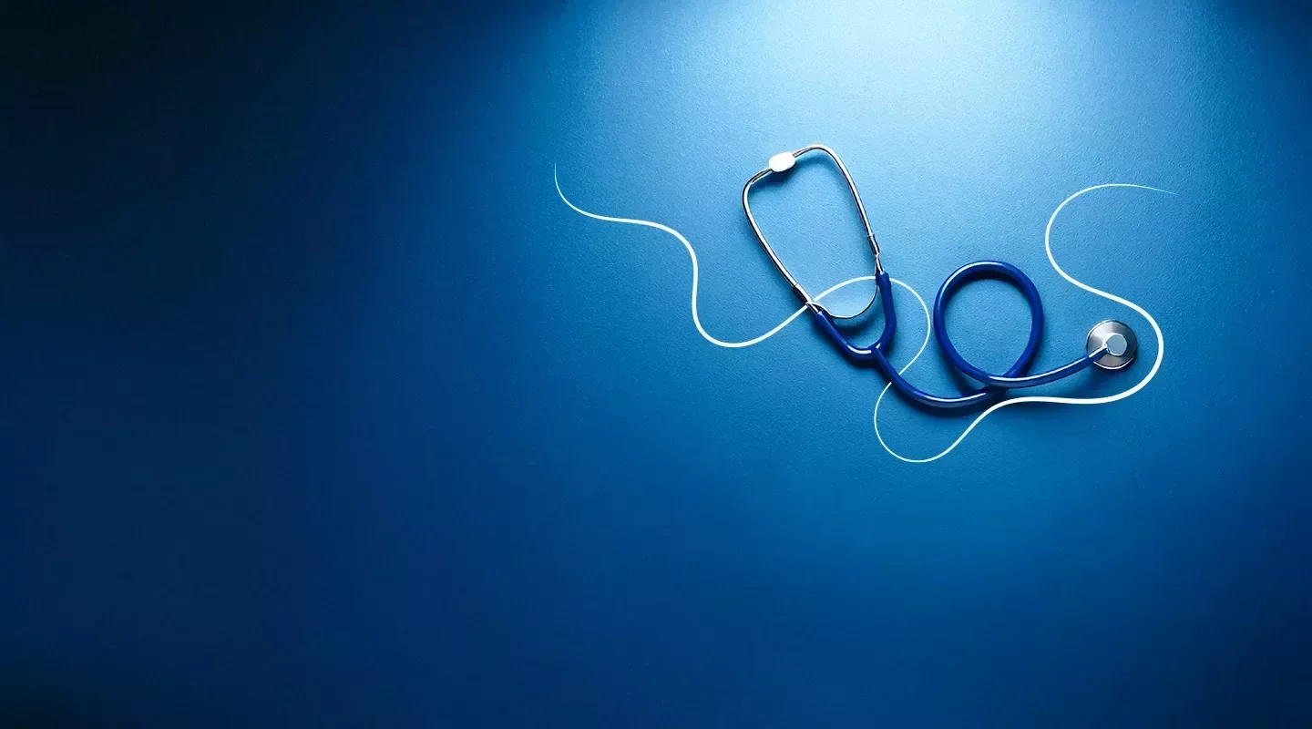 Estetoscopio azul sobre fondo azul, asociado a salud y cuidado profesional.