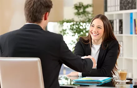 Dos personas dándose la mano en una reunión de trabajo.