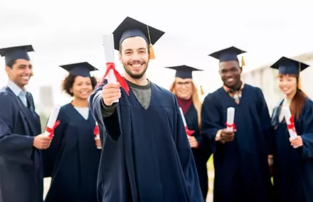 Grupo de graduados sonriendo con togas y birretes.
