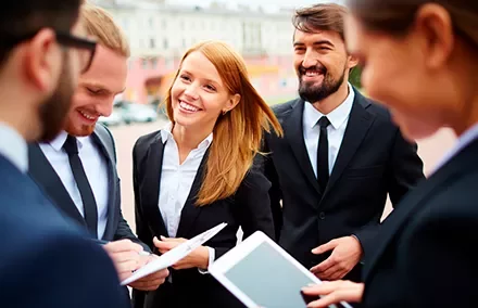 Grupo de personas en trajes sonriendo mientras revisan documentos.