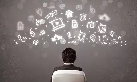 Hombre de espaldas frente a una pizarra con iconos de tecnología y comunicación en el aire.