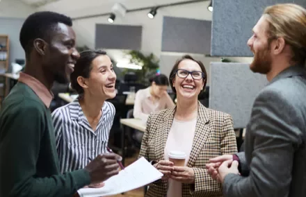 Grupo diverso de personas riendo en una oficina.