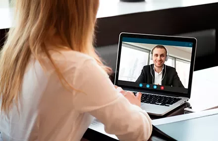 Mujer en videollamada con hombre usando auriculares en la computadora portátil.